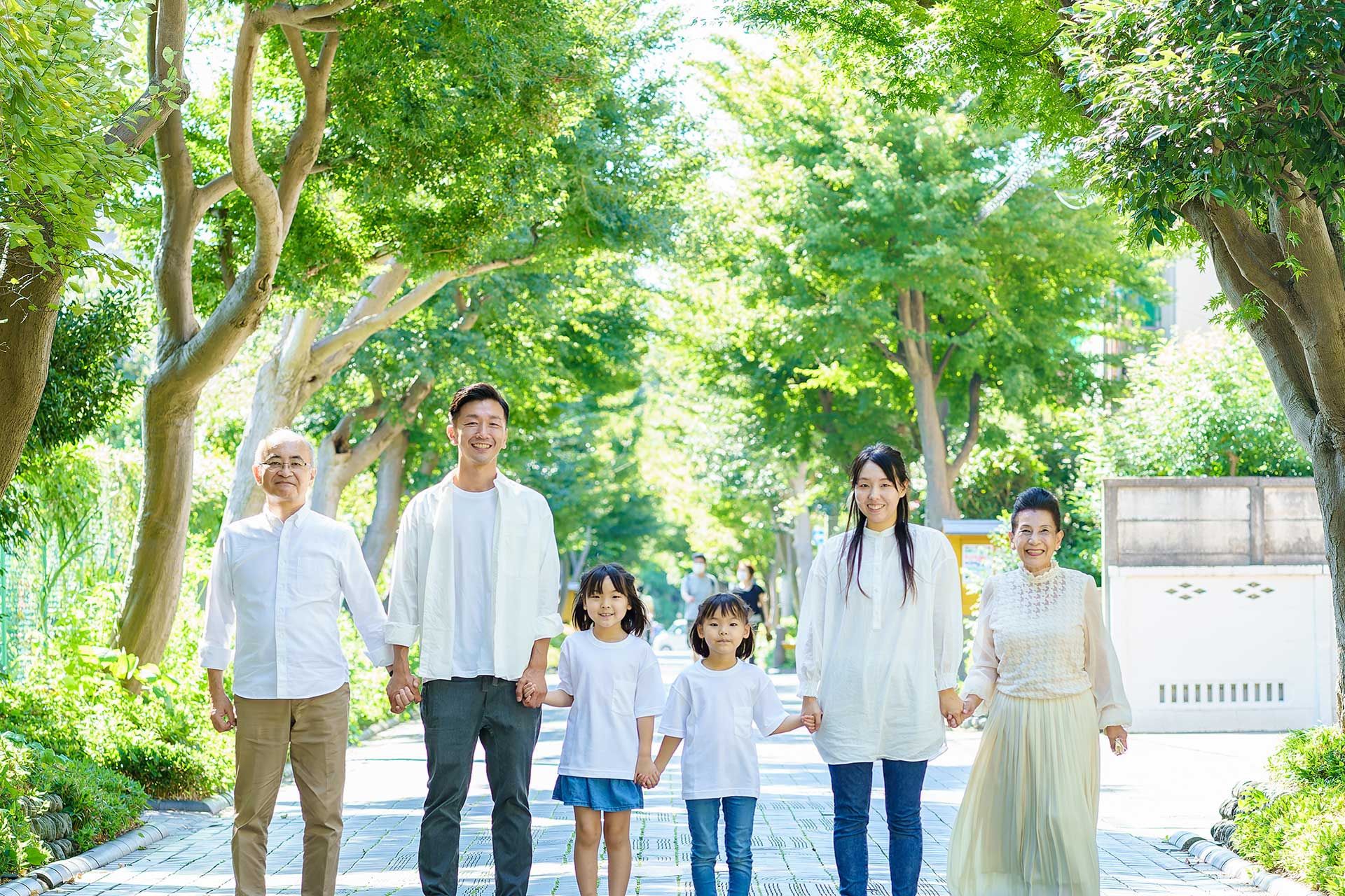 緑の木々の中で手をつなぐ幸せそうな家族